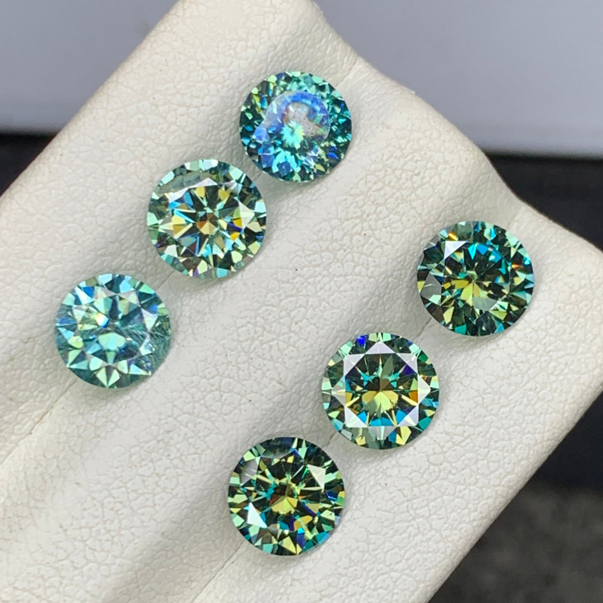 Bluish green moissanite lot on white background
Round cut moissanite size range comparison
