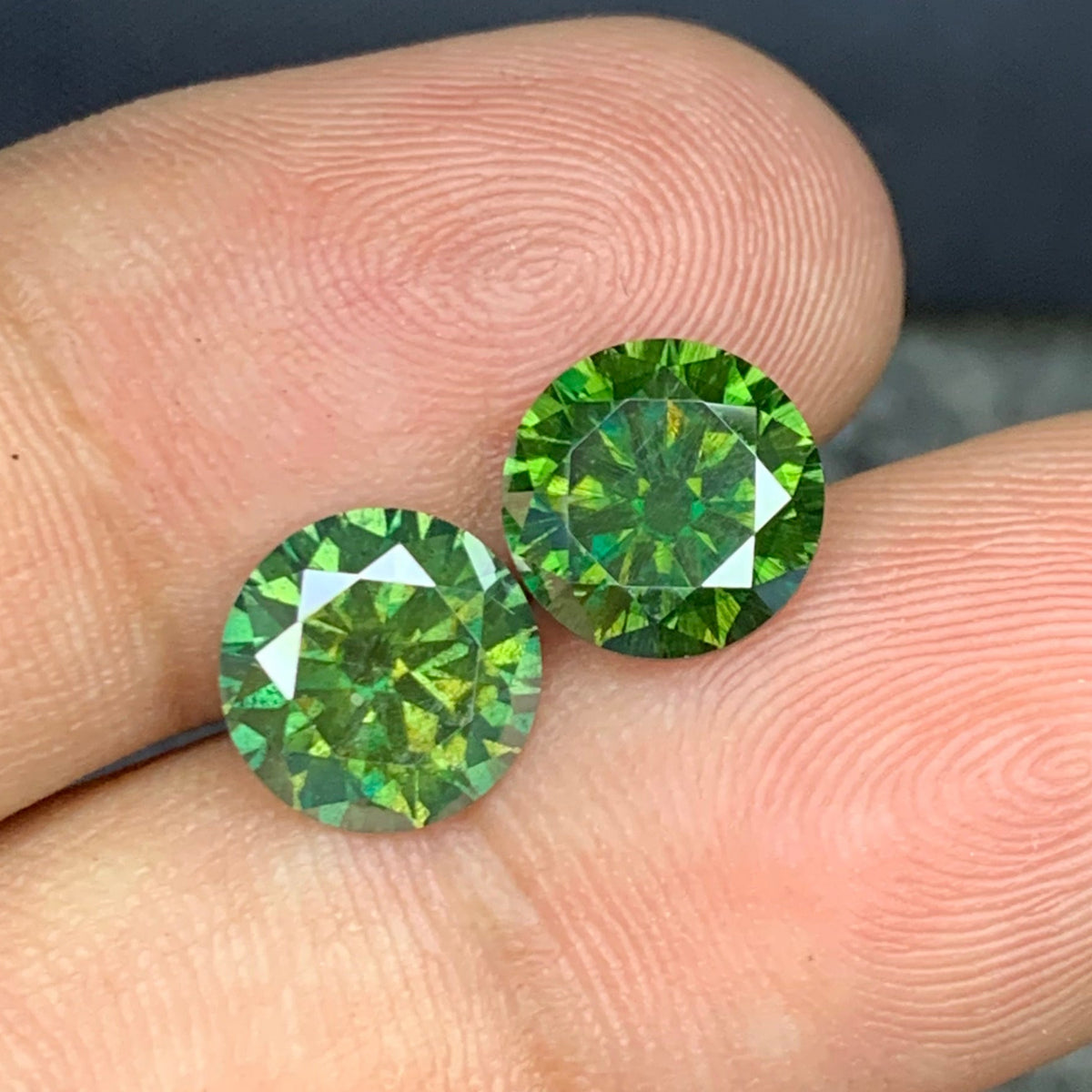 Green moissanite pair held for scale
Moissanite pair reflecting light showing brilliance and fire