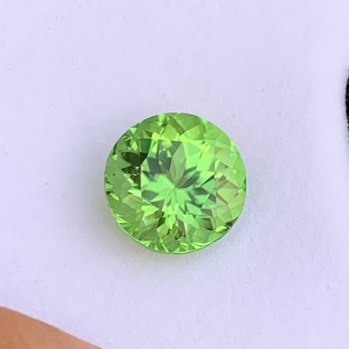 Round cut gemstone dimensions 14.84 x 14.60 x 10.72mm
Pea green peridot held for scale
